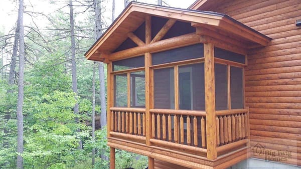 A screened in porch on a log home.