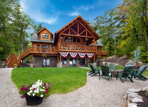 exterior view of cedar log home package with fire pit and chairs in foreground