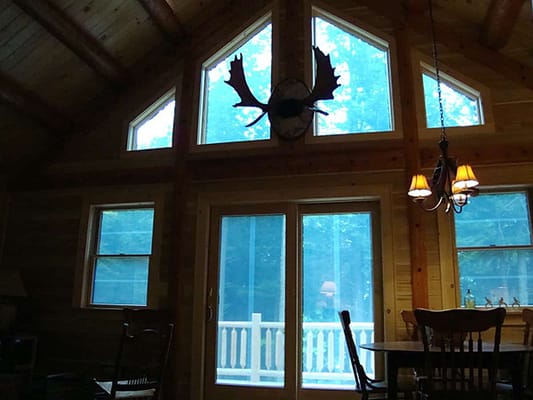 Moose antlers loom intriguingly over transom windows in a log cabin.