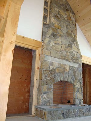 A Stone fireplace that reaches to the top of a vaulted ceiling.